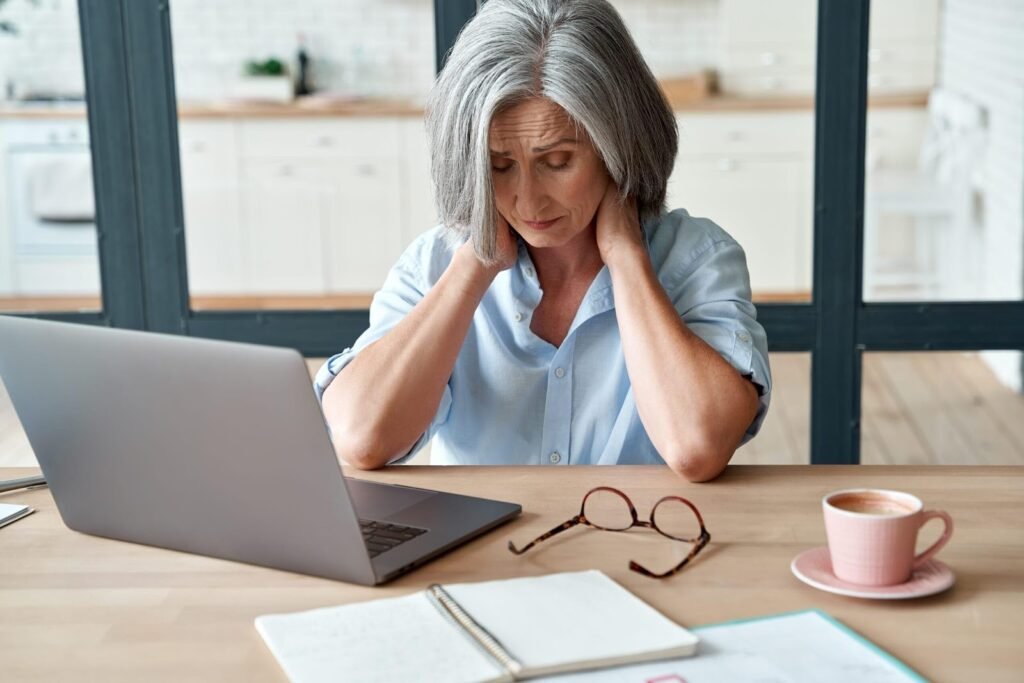 A stressed woman sitting at her desk with her head in her hands.